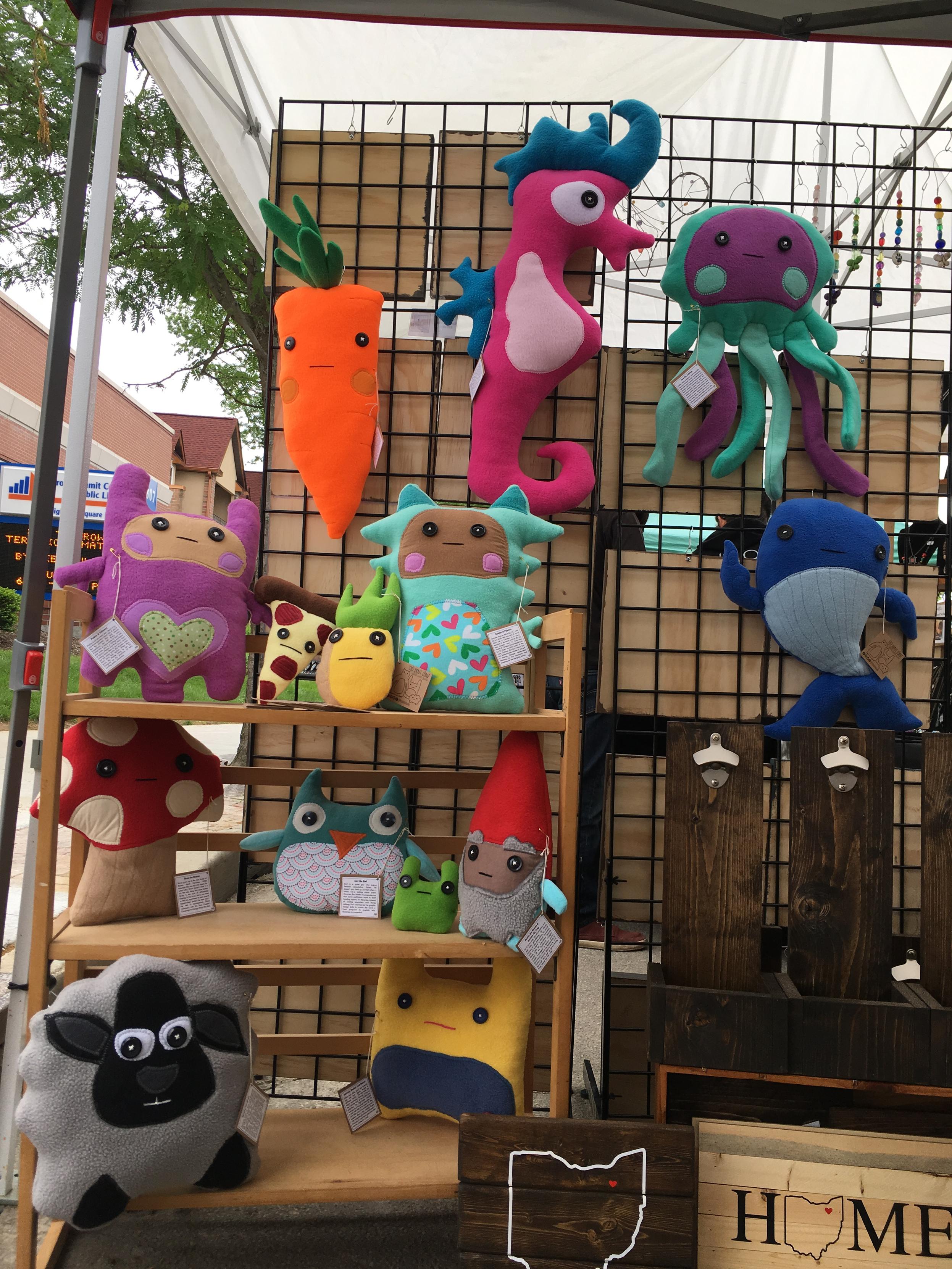 plushies of a carrot, a seahorse, a jellyfish, a pineapple and pizza couple, a gnome and toad couple, a mushroom, an owl, a kid in pink pajamas, a kid in blue monster pajamas, a whale, a sheep, and a yellow monster [which is probably the closest thing to a repeat doll i've ever made].